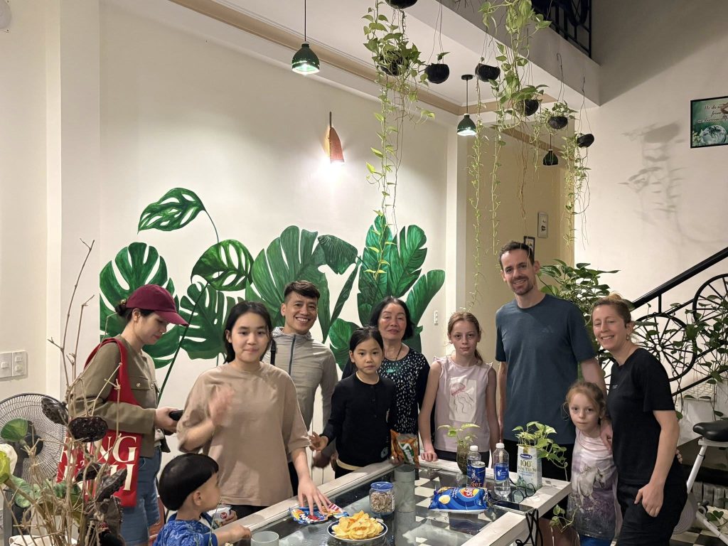 Du khách quốc tế và gia đình địa phương sinh hoạt chung tại Huế Eco Homestay trong không gian xanh, gần gũi.