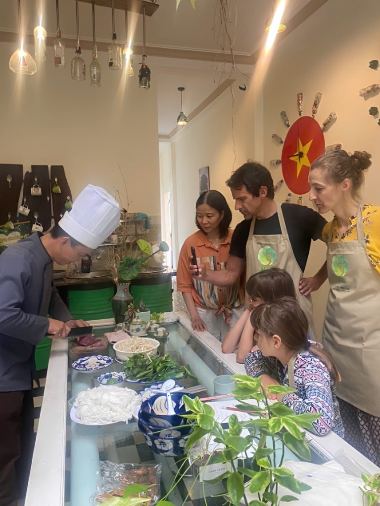 Lớp học nấu ăn tại Huế Eco Homestay với du khách quốc tế và trẻ em cùng học làm món ăn truyền thống Huế.